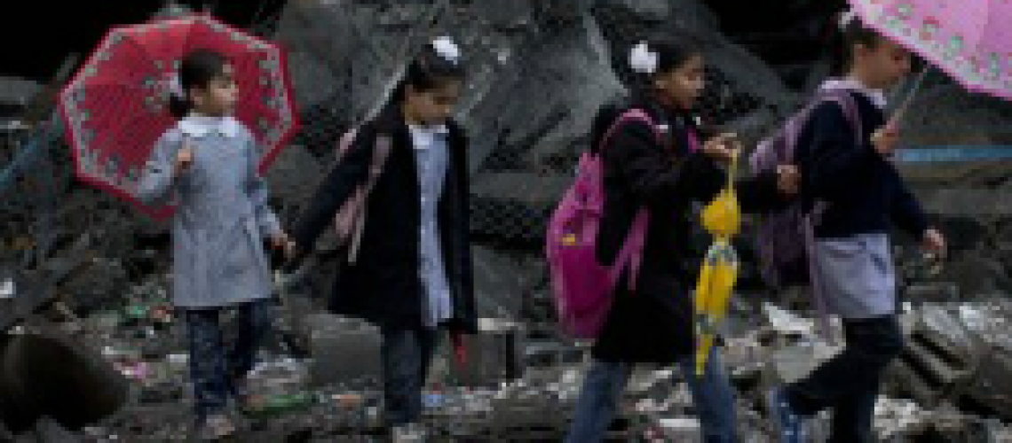 Schoolchildren walk in debris by a damaged school in Gaza City. (Huffington Post)