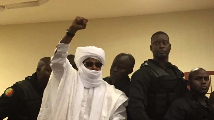 Chad's former dictator Hissene Habre raises his hand during court proceedings in Dakar, Senegal, Monday, May 30, 2016. Judge Gberdao Gustave Kam declared Habre guilty and sentenced him to life in prison for crimes against humanity, war crimes and torture, in a packed courtroom, Monday.(AP Photo/Carley Petesch)